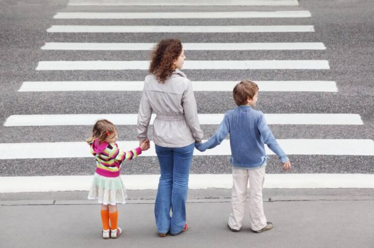 young mother holds hand of his little daughter and son and stand