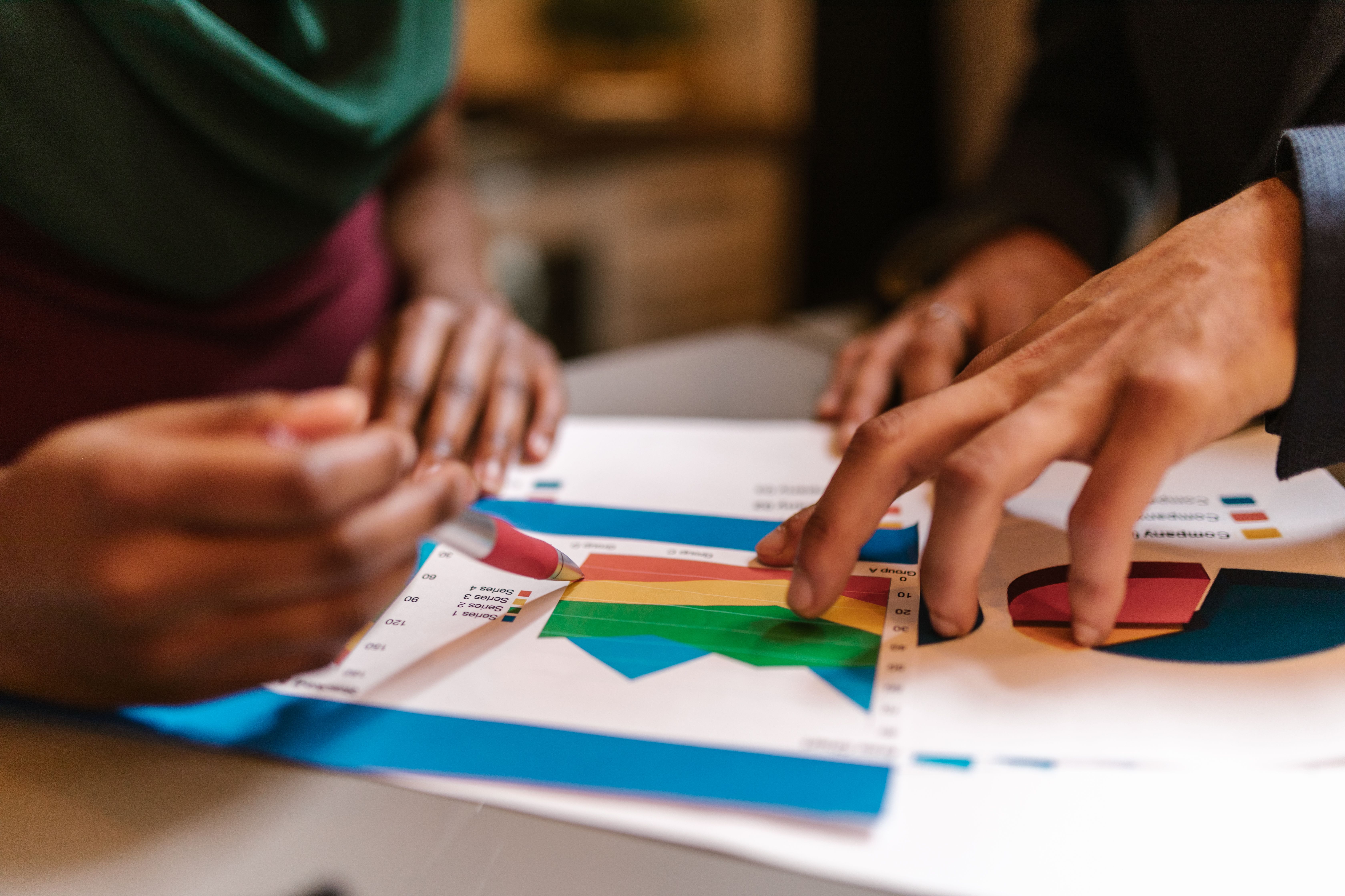 Collaborators reviewing colorful graphs and documents during an impact reporting meeting.